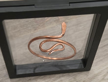 Load image into Gallery viewer, A copper snake bangle displayed inside a black shadow box frame on a light wood surface.