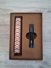 Load image into Gallery viewer, Rose gold bracelet and black tool in a brown box on a wooden surface