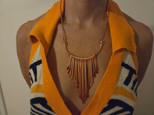 Load image into Gallery viewer, A close-up of a person wearing a pure copper statement necklace over a yellow and navy patterned knit top.