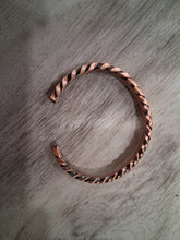 Load image into Gallery viewer, Copper bracelet with a braided design on a wooden surface
