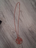Copper necklace with a circular pendant on a wooden surface