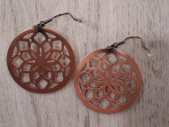 Copper filigree earrings on a wooden surface