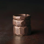 Stack of bronze rings with geometric design on a dark background