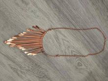 Load image into Gallery viewer, A  pure copper statement necklace featuring a fan-like cluster of flat copper bars attached to a delicate chain, laid flat on a gray wood-textured surface.

