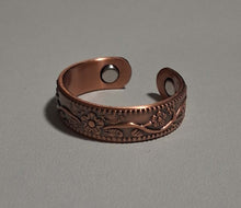 Load image into Gallery viewer, A copper-colored adjustable cuff ring with an embossed floral pattern, displayed on a neutral gray background.
