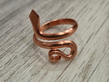 Load image into Gallery viewer, A pure copper snake wrap ring with a hammered texture, displayed on a light gray wood-grain surface.
