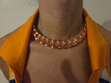 Load image into Gallery viewer, A close-up of a person wearing a chunky, hand woven coppe necklace with a bright yellow-orange knit top underneath.
